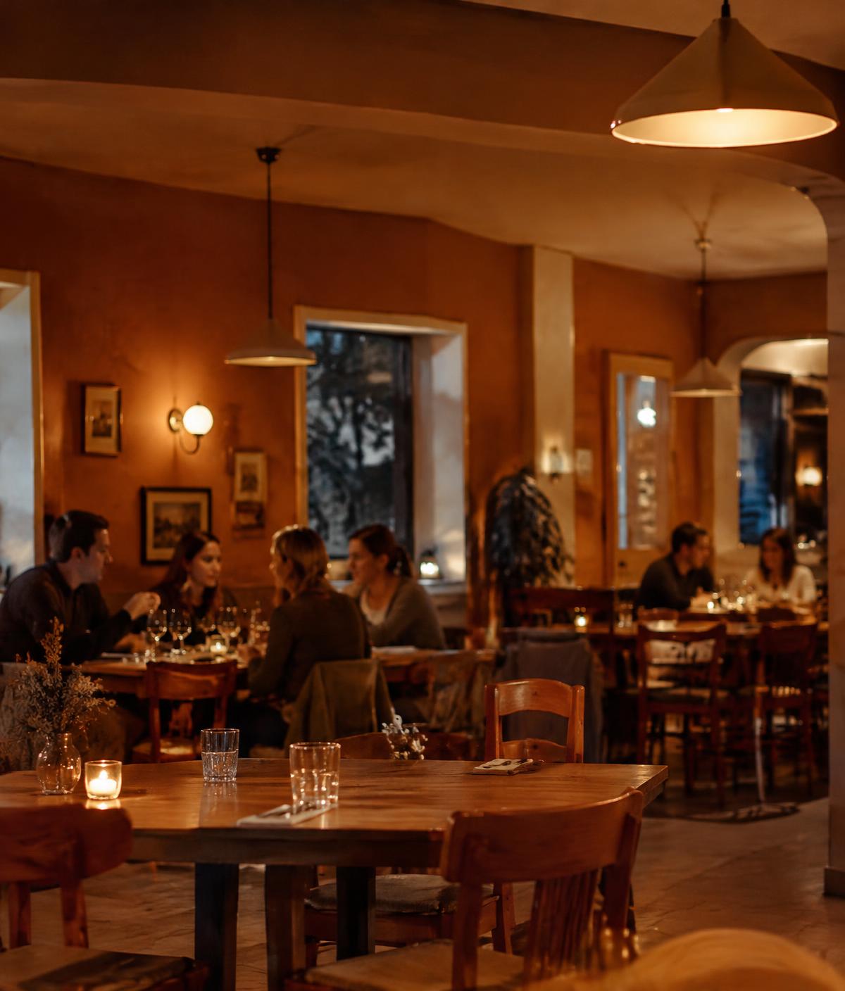 Warmly lit dining room with oak tables and pendant lights